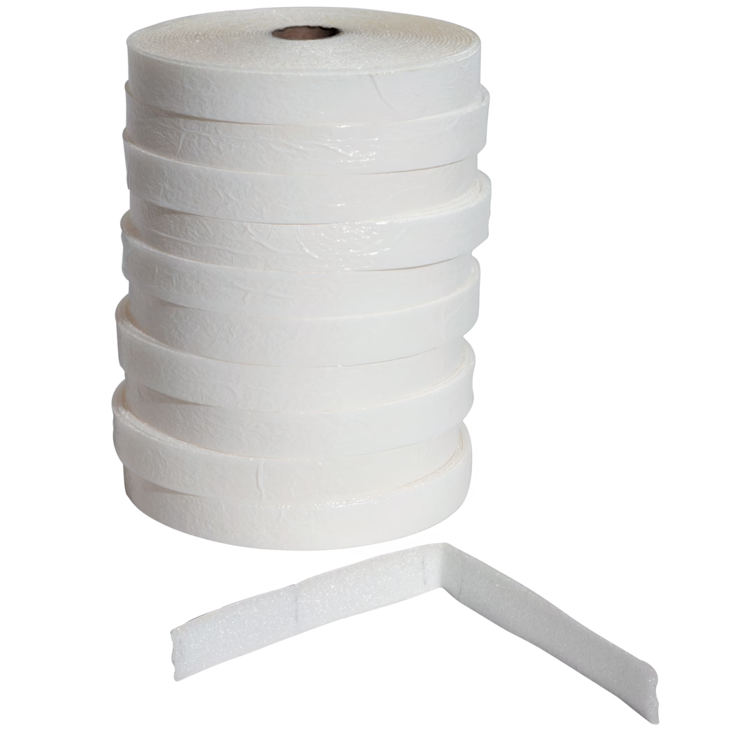UZIN_Dummy_ES 50_5_2014-02 Une pile verticale de plusieurs rouleaux de ruban en mousse adhésive blancs à surface texturée sur fond blanc ; une bande de mousse est posée devant et pliée à angle droit, révélant son épaisseur et sa texture poreuse. Les rouleaux présentent un noyau en carton et une couche extérieure légèrement brillante, adaptés au calfeutrage, à l'amortissement, à l'étanchéité ou à l'isolation.
